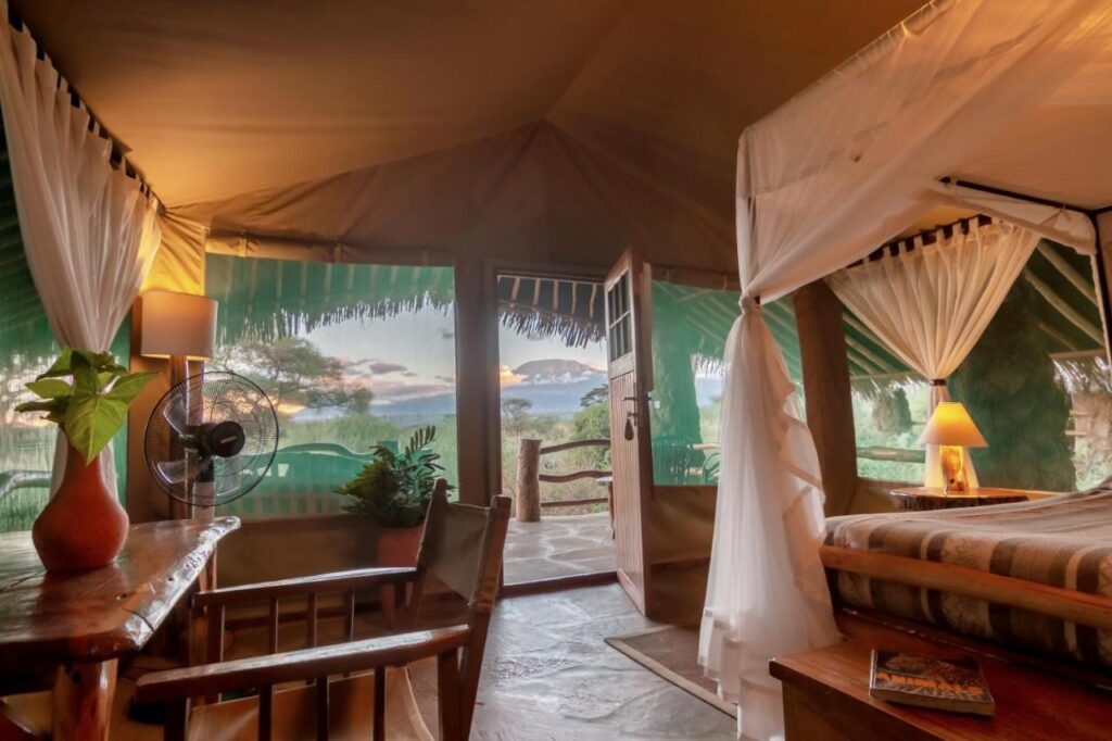 Ett tält på Kibo Safari Camp öppet mot terrassen, med Kilimanjaro i fjärran i skymningen