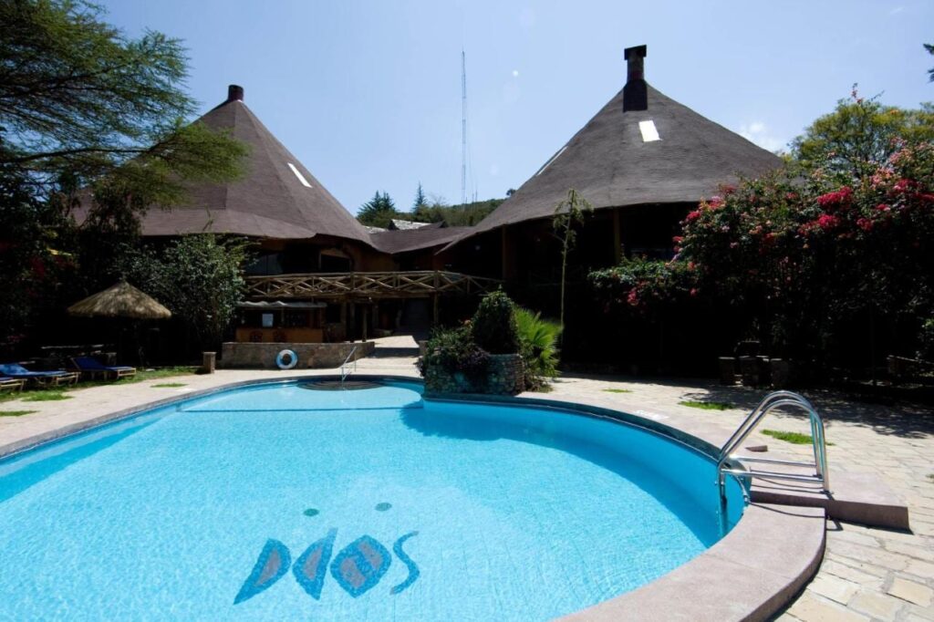 Poolen på Mara Sopa Lodge, framför byggnader med stora koniska halmtak