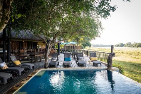Poolen på Umkumbe Safari Lodge och träterrassen, ovanför flodens gräsbevuxna strand